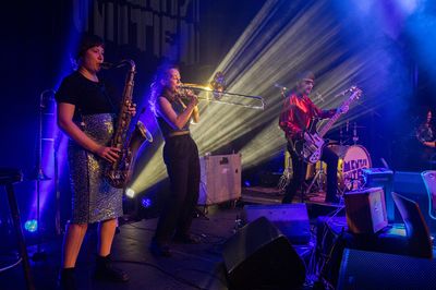 Mentsh United live auf der Bühne mit Saxofon, Posaune und Bass im Scheinwerferlicht